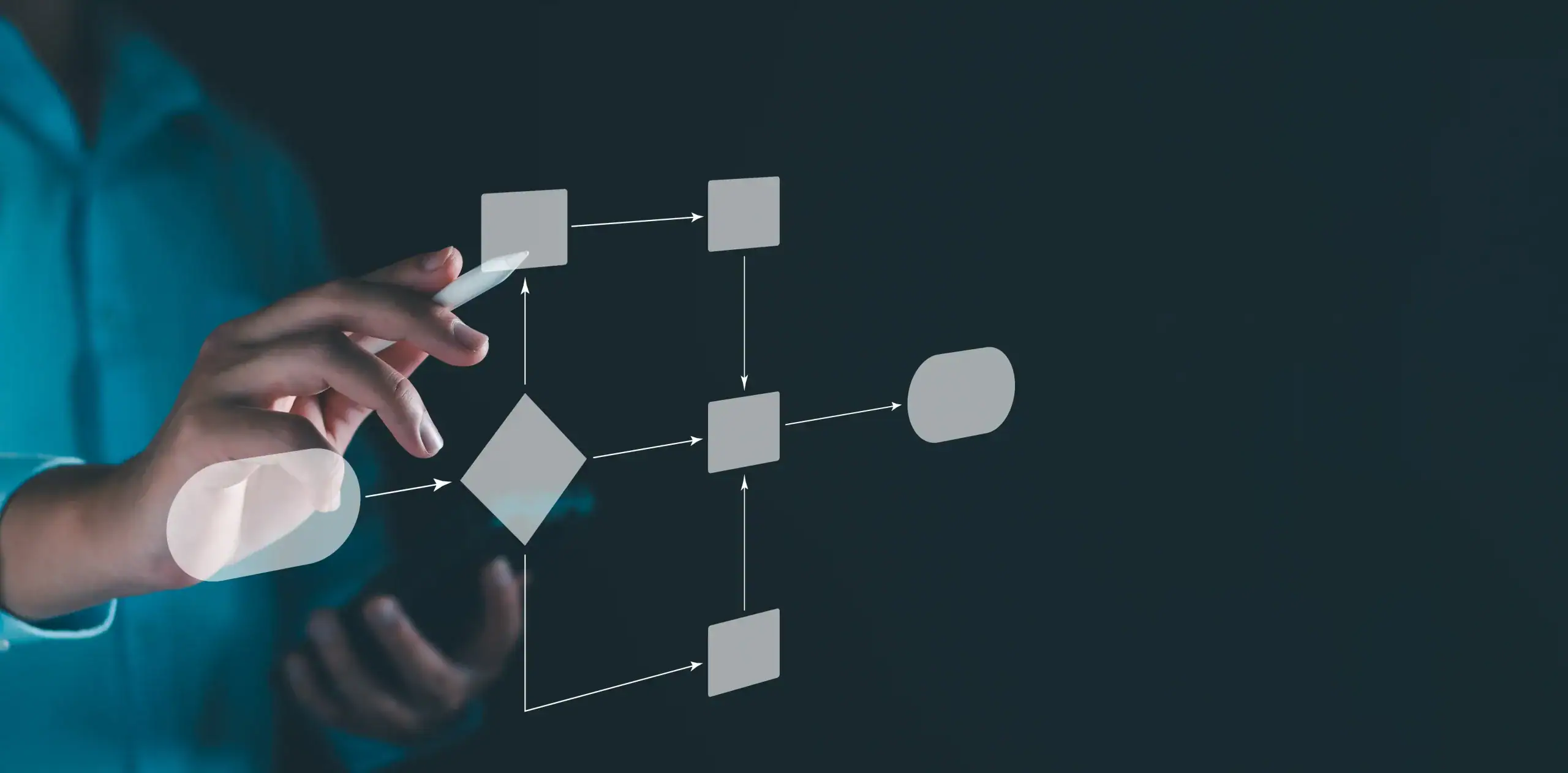 Close-up of a person in a teal shirt using a stylus while holding a smartphone, interacting with a floating digital flowchart on a dark background; the translucent diagram shows squares, a diamond decision node, rounded terminals, and arrows connecting the steps. No recognizable figures, landmarks, or brands are visible.